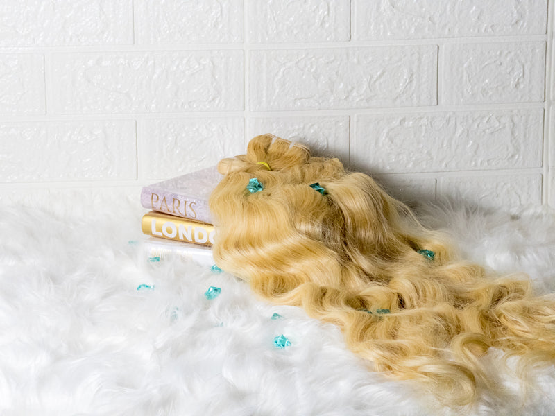 Luxury Indian hair extensions in wavy blonde, displayed on stylish books for a chic look