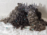 Opulent gray curly hair bundles displayed with clips on a soft white background