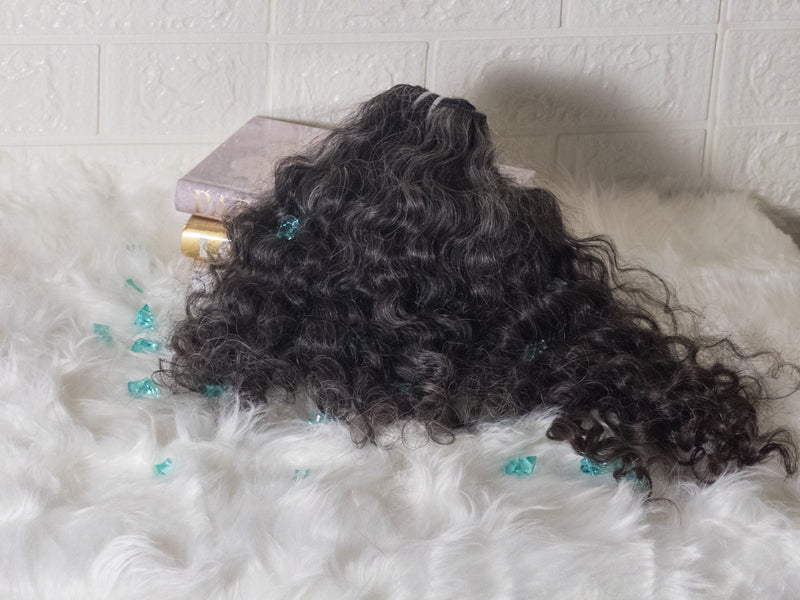 Opulent gray curly hair bundles displayed on a fluffy surface with decorative elements
