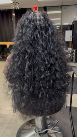 Long black raw Indian curly hair bundles styled for a natural look in a salon setting