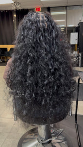 Long black raw Indian curly hair bundles styled for a natural look in a salon setting